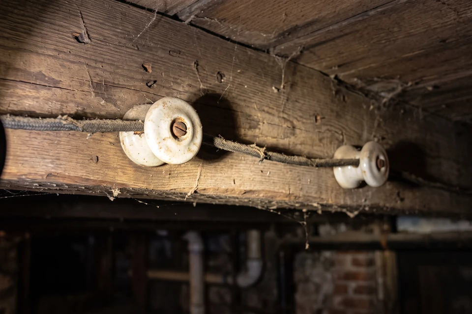 Aged cloth insulation on a wire supported by porcelain knobs in an older NYC building.