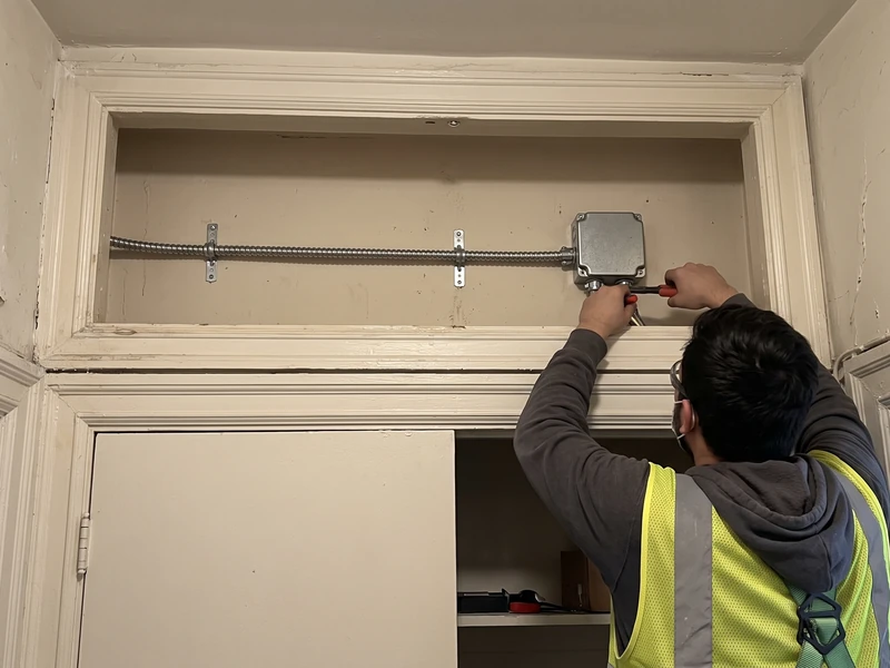 A short cable route and closed junction box above an interior closet in an older NYC apartment.