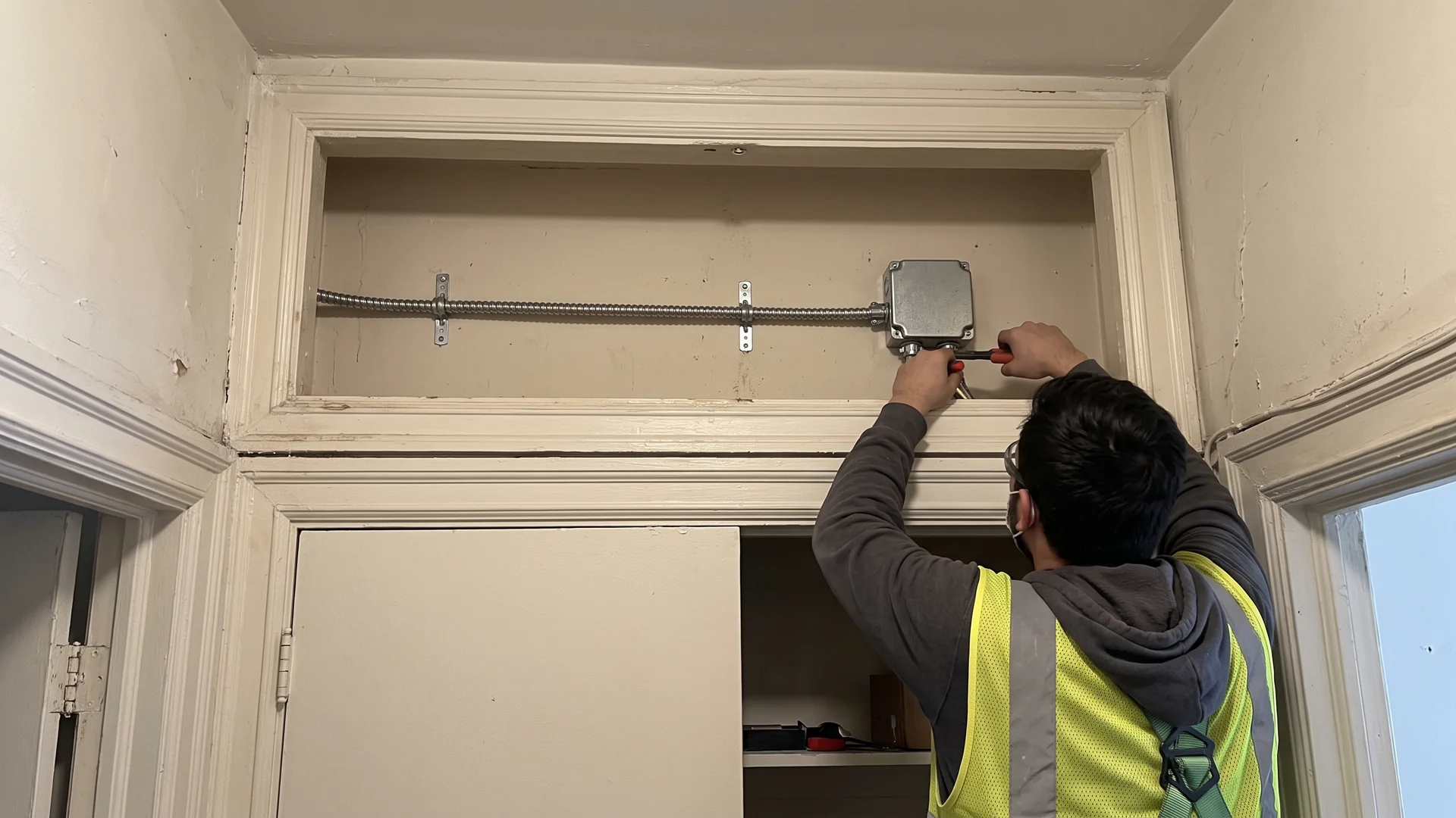 A short cable route and closed junction box above an interior closet in an older NYC apartment.